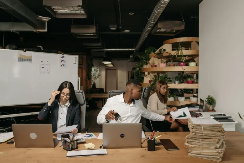 Tim divisi operasional bekerja bersama di meja kantor dengan laptop dan dokumen